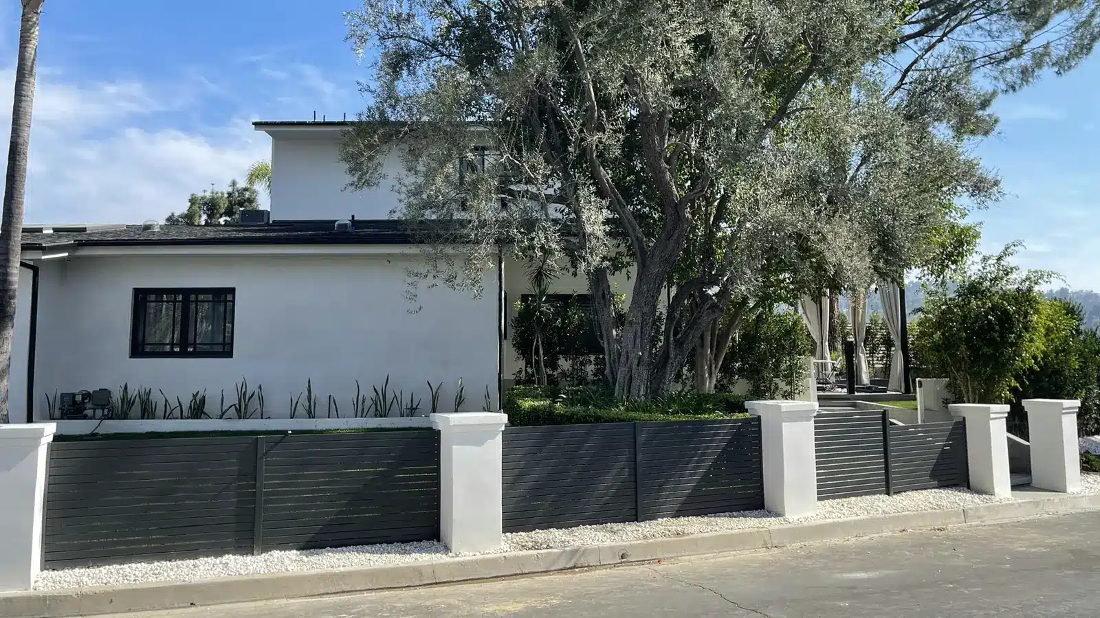 Modern horizontal aluminum slat fence with white stucco pillars at a California home